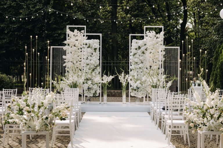 Freie Trauung im Freien mit weißem Blumenaltar, Lichterketten und weißen Stühlen