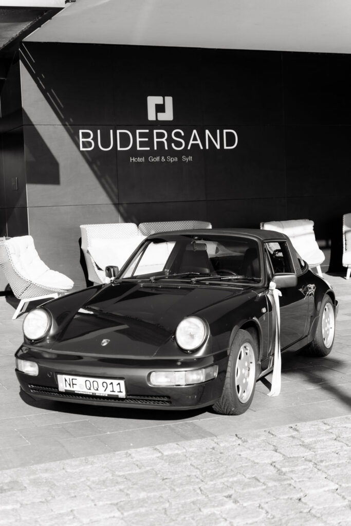Schwarzer Porsche als Hochzeitsauto vor dem Eingang des Budersand Hotels auf Sylt