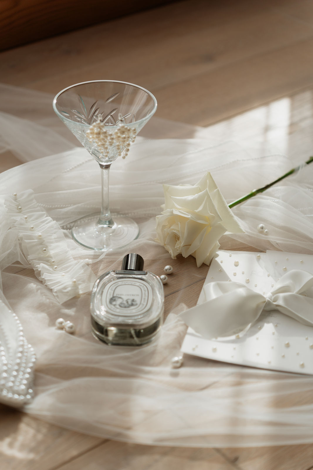 Hochzeitsdetails auf dem Brautschleier: Parfumflakon, weiße Rose und Perlen