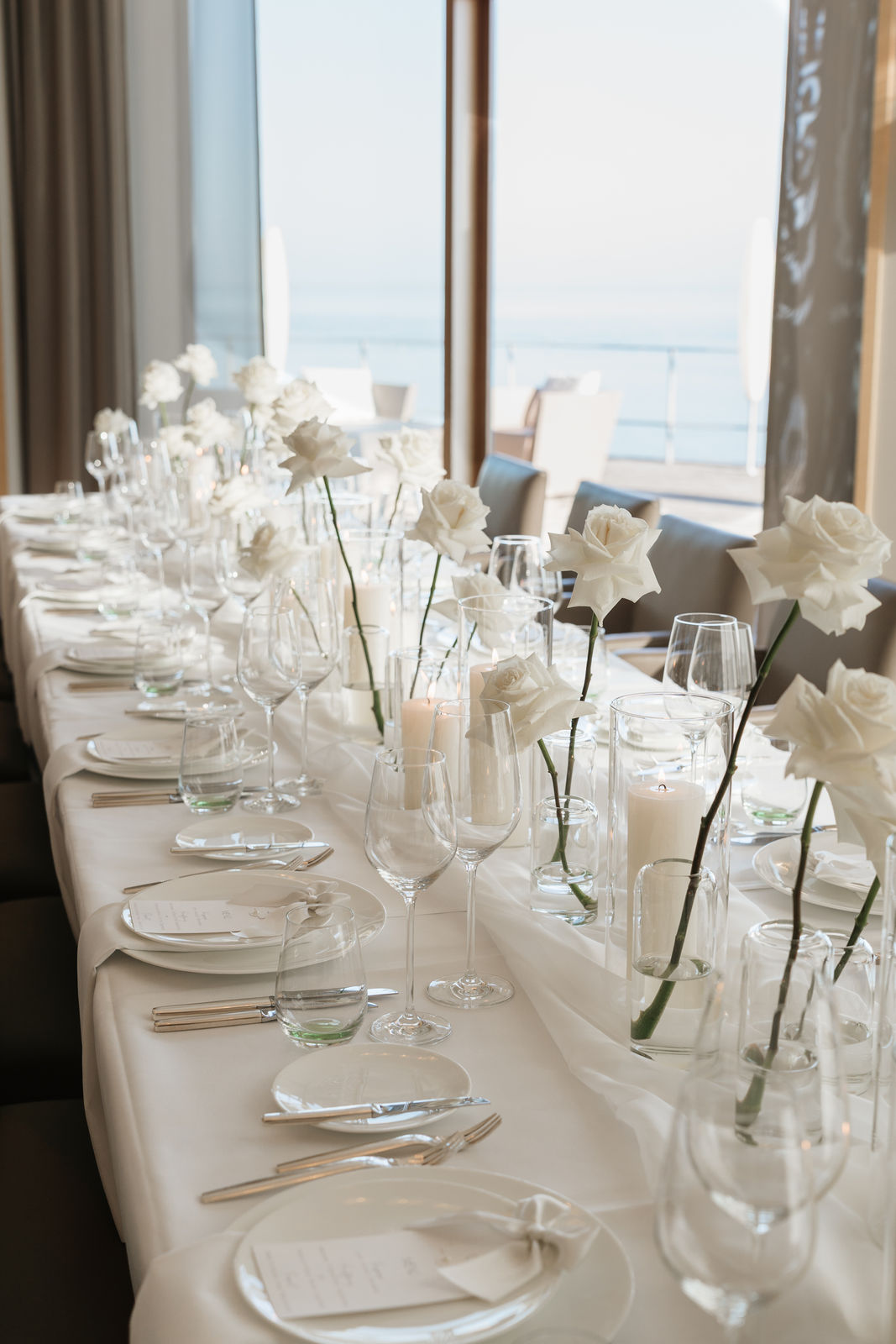 Festlich gedeckte Hochzeitstafel mit weißen Rosen und Kerzen mit Blick auf das Meer