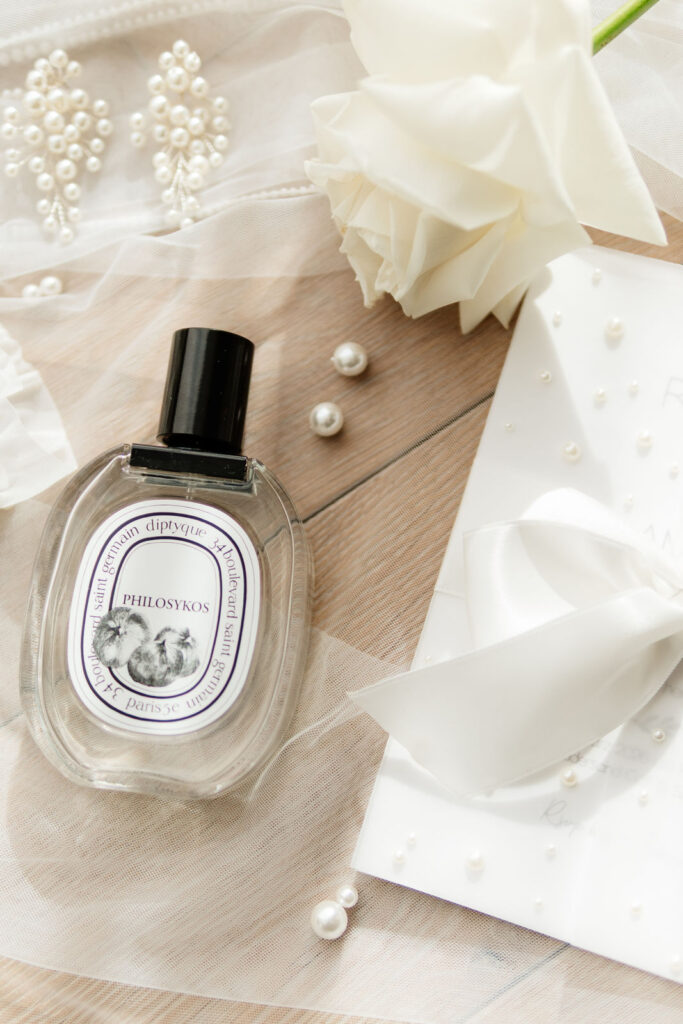 Parfumflakon, Perlen und eine weiße Rose auf dem Brautschleier