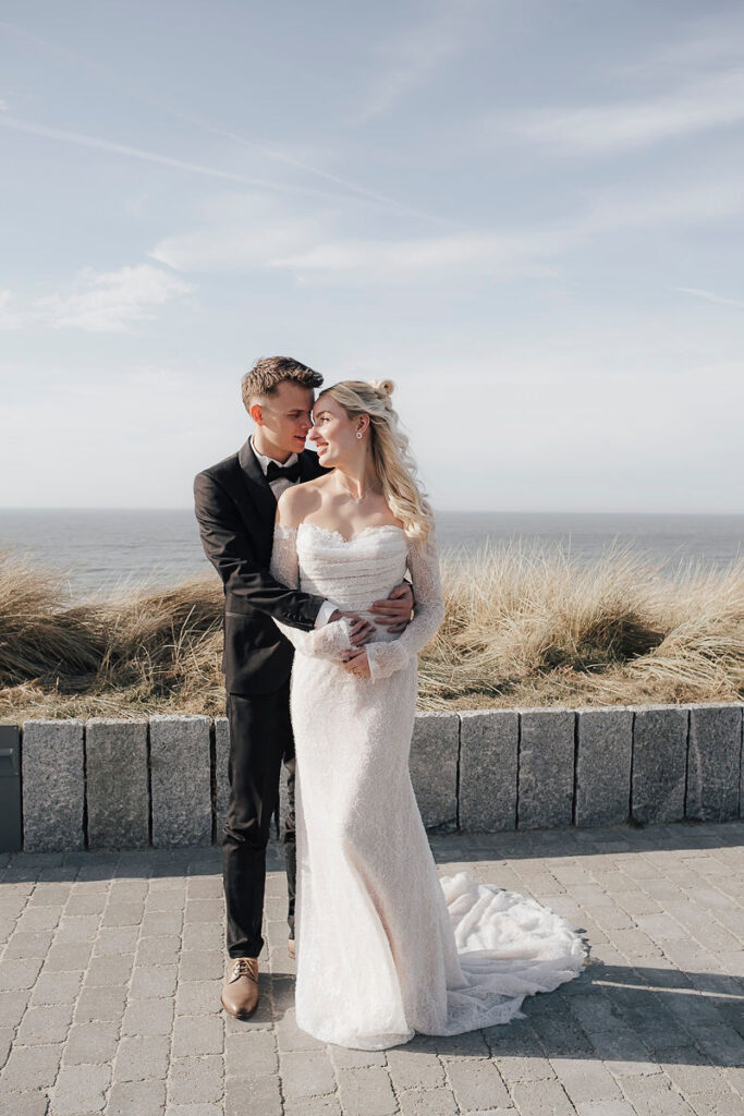 Brautpaar an der Strandpromenade von Sylt, im Hintergrund Dünen und Meer