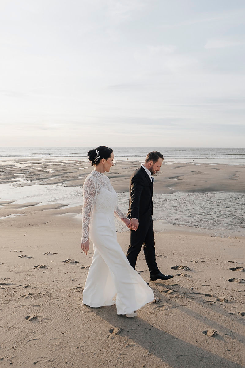 Brautpaar läuft Hand in Hand über den Strand von Wenningstedt auf Sylt