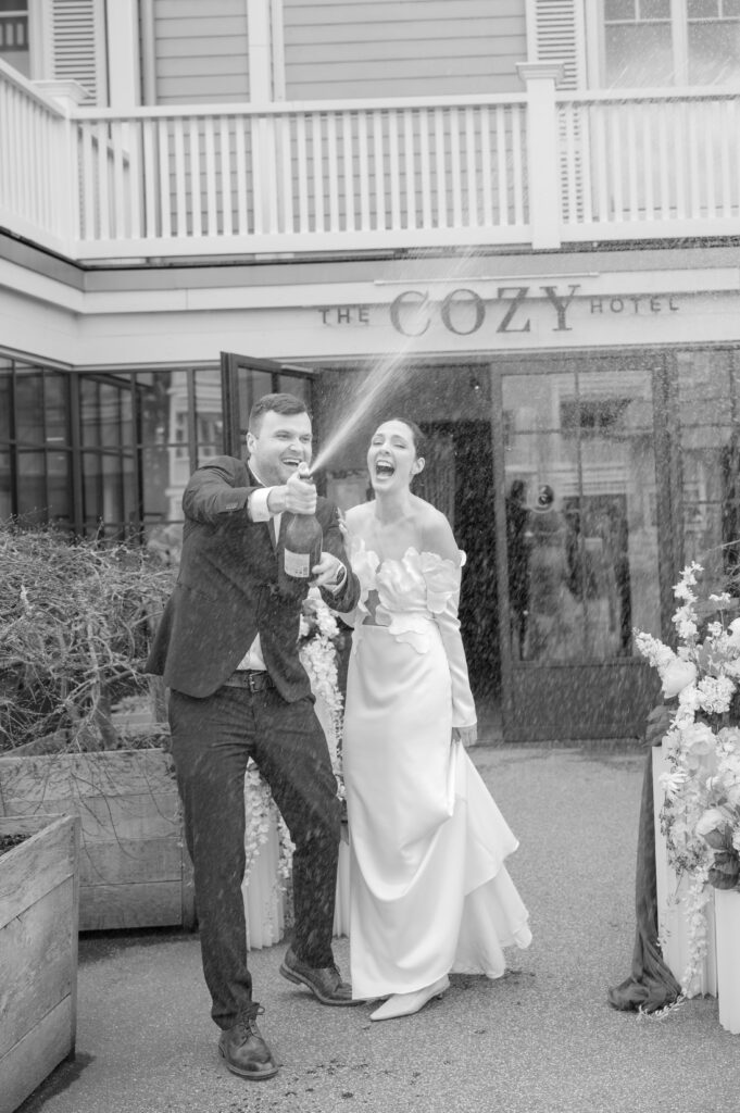 Brautpaar lässt vor dem Eingang des The Cozy Hotels den Champagner spritzen
