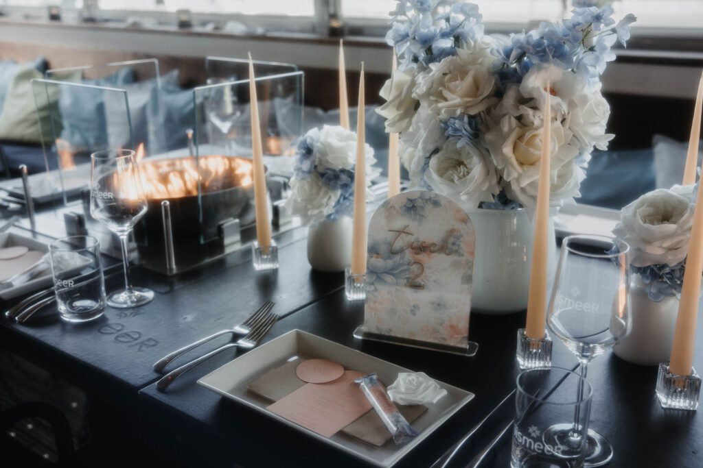 Gedeckte Hochzeitstafel mit blauen und weißen Blüten und Kerzen im Iismeer auf Sylt