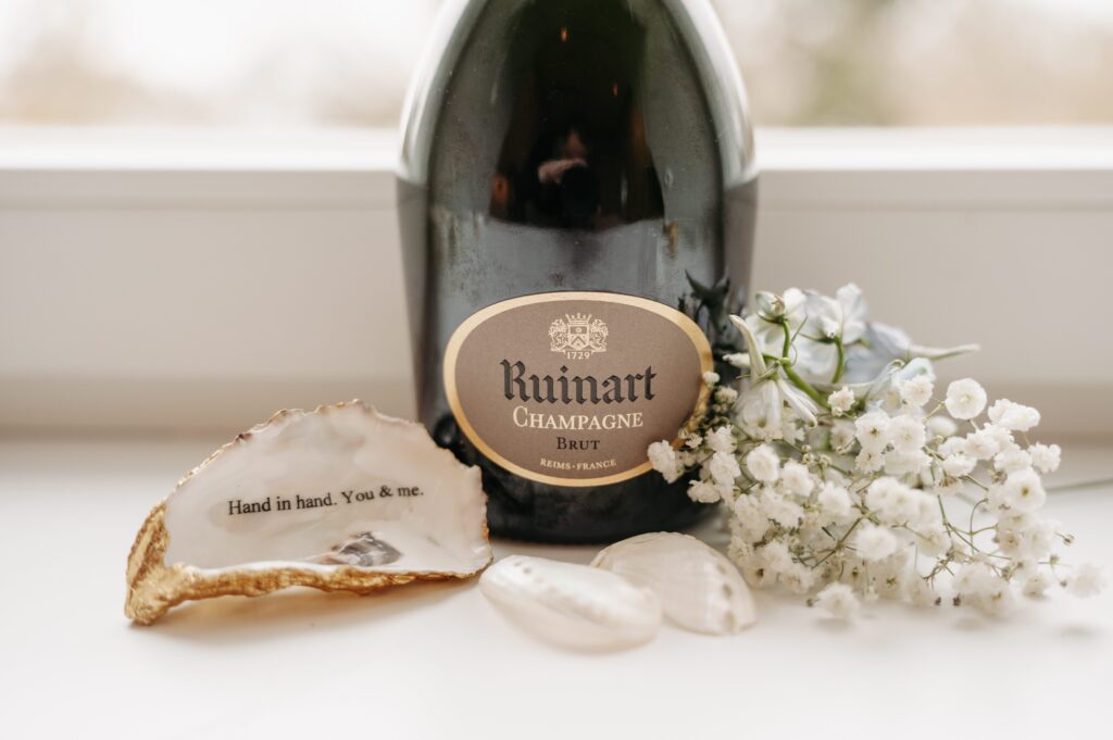 Champagnerflasche mit gravierter Austernschale und Schleierkraut als Hochzeitsdetail