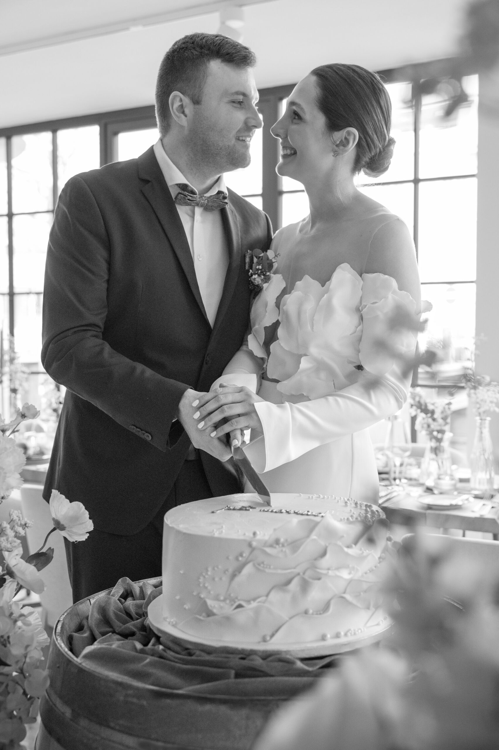 Brautpaar schneidet gemeinsam die weiße Hochzeitstorte an