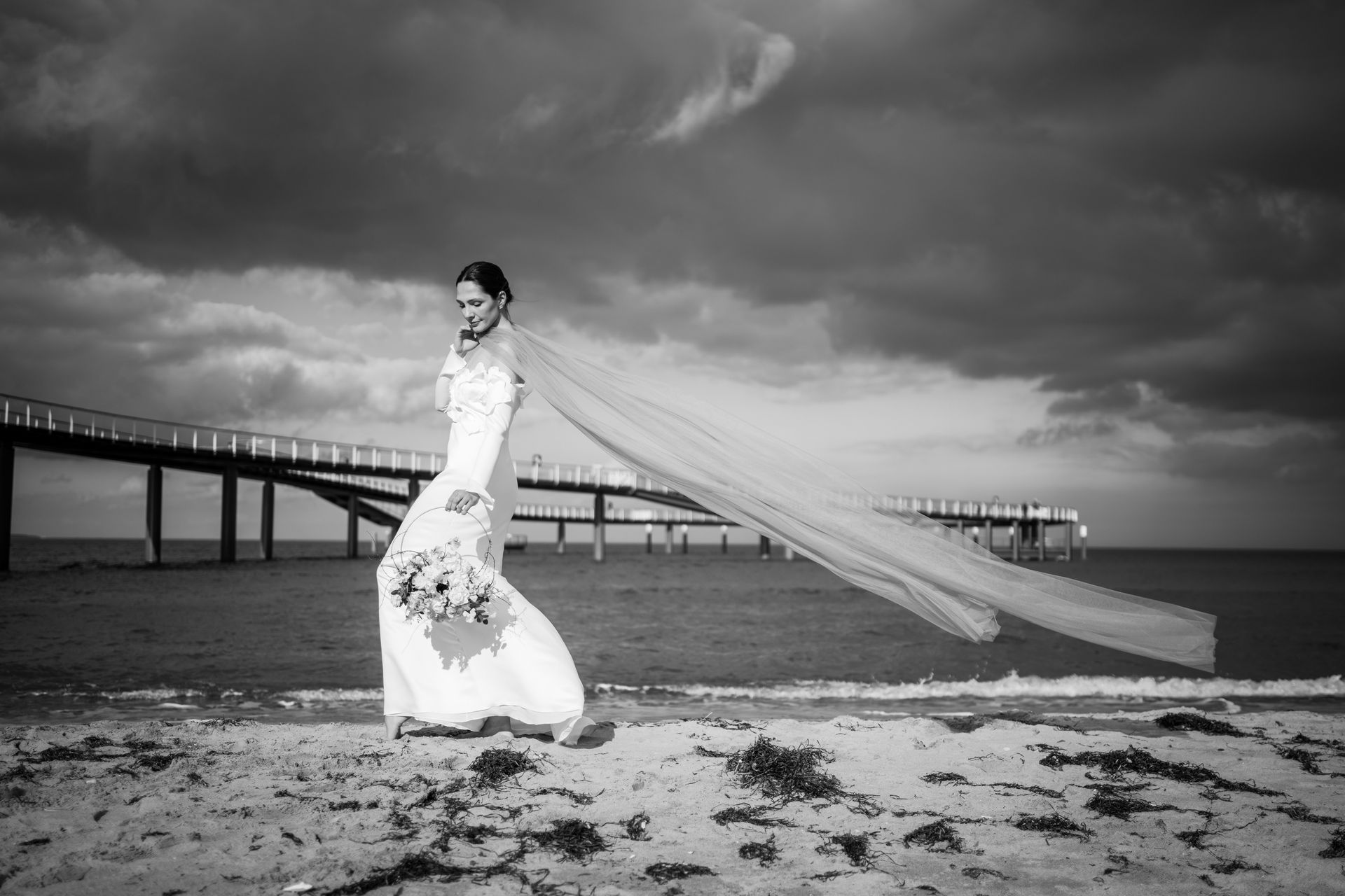 Braut mit wehendem Schleier am Strand vor der Seebrücke am Timmendorfer Strand