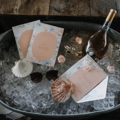 Sektkühler mit Eis, Roséwein, Muscheln und Hochzeitspapeterie